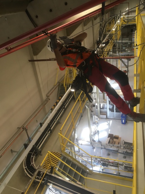 Cordiste descendant le long de passerelles dans un site industriel